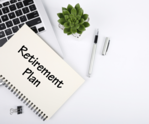 computer and pad of paper with retirement plan written on it